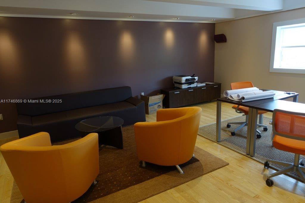 An office space features a dark sofa, orange chairs, a desk, and hardwood flooring — 6130 NE 4th Ct, Miami FL 33137, MIAMI, FL