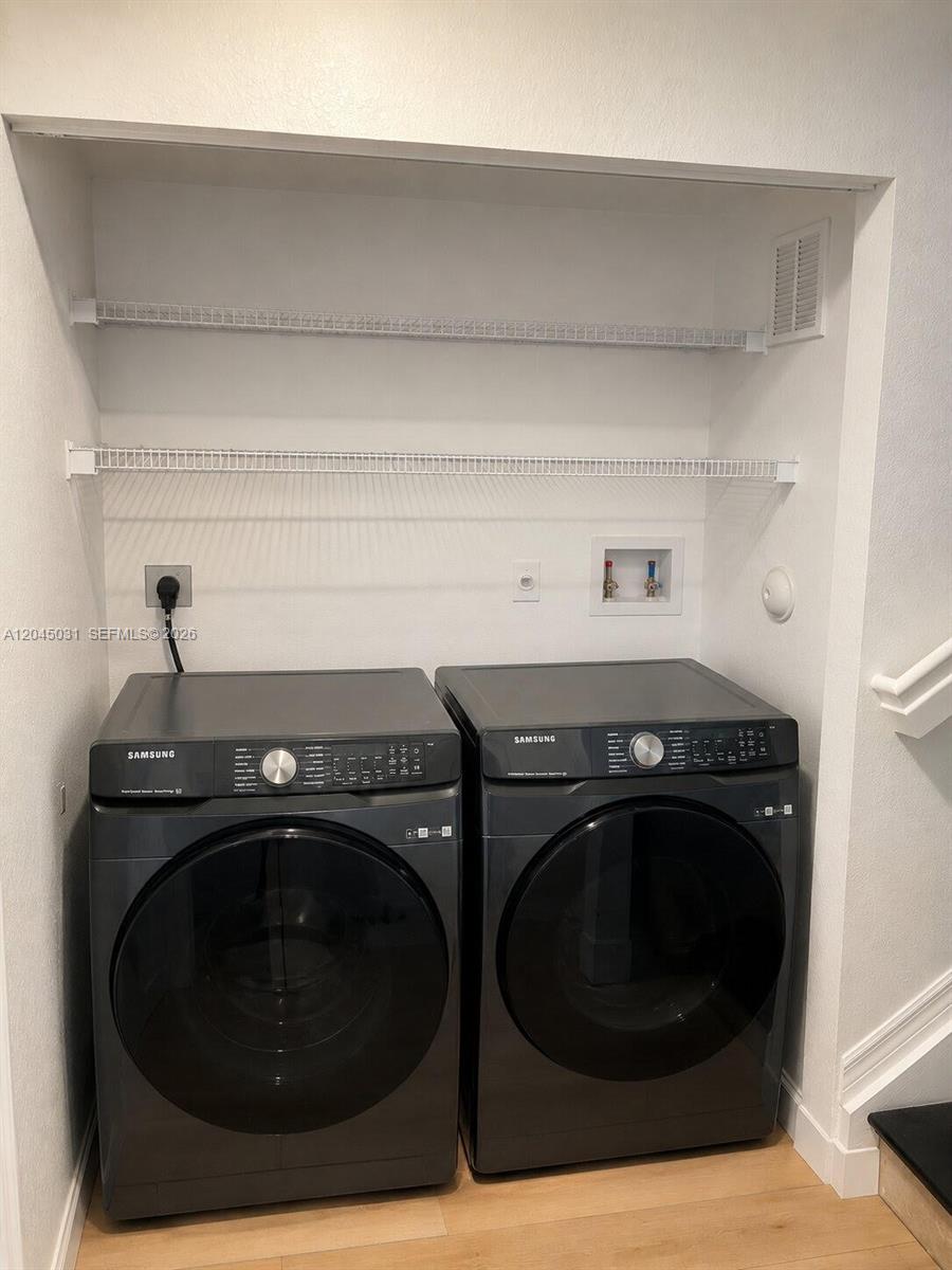 A laundry closet features two dark gray Samsung appliances beneath two white wire shelves — 10885 NW 89th Ter # 203, Doral FL 33178, DORAL, FL