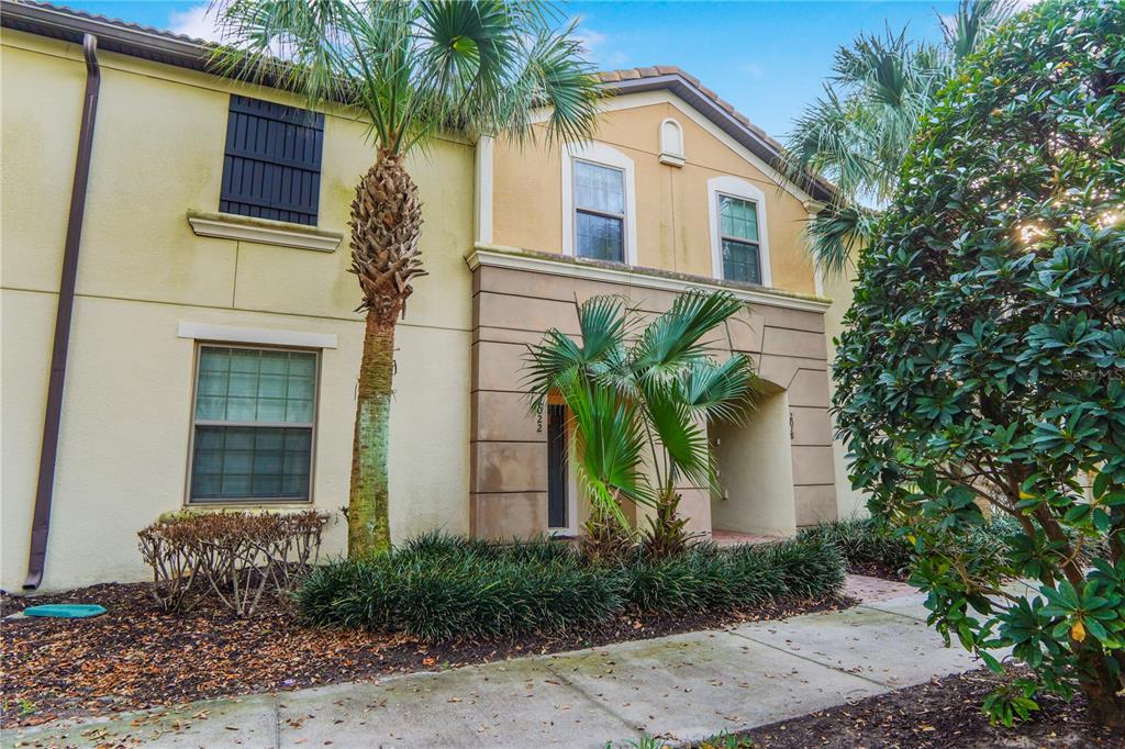 A two-story tan stucco townhouse exterior features a palm tree and a landscaped front yard — 2022 MAJORCA DRIVE, KISSIMMEE, FL