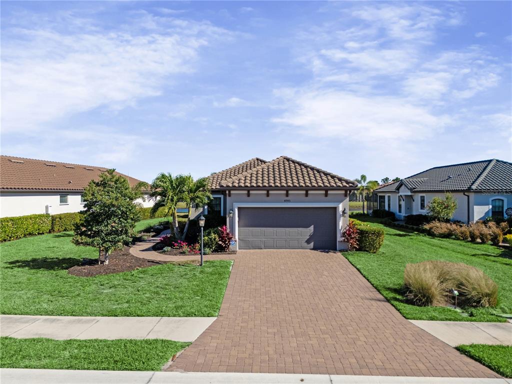 A single-story house with a tiled roof, a paved driveway, and a two-car garage — 4743 MOTTA COURT, BRADENTON, FL