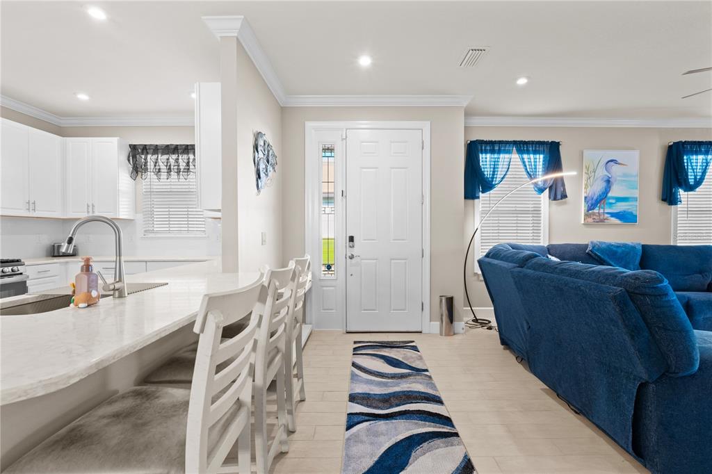A kitchen island with bar stools faces a living area with a blue sectional sofa — 4743 MOTTA COURT, BRADENTON, FL