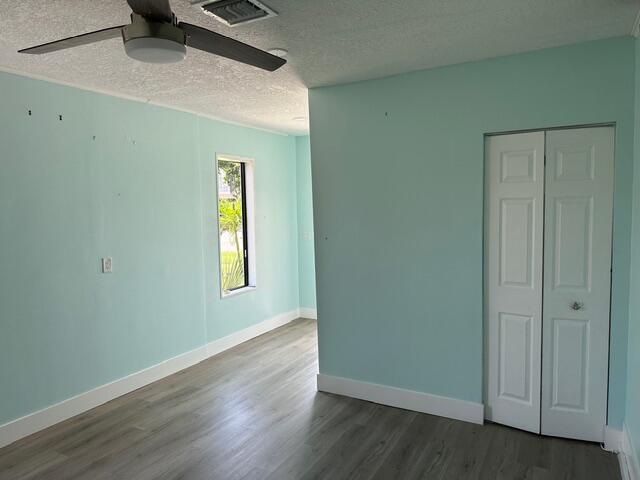 A bedroom with light blue walls, wood-look flooring, a ceiling fan, and a white closet — 907 SE Lake Street, Stuart FL 34994, STUART, FL