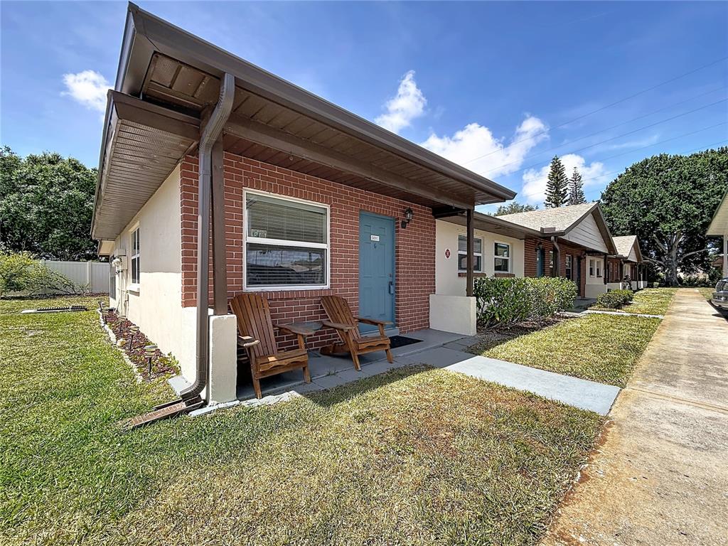 A single-story brick building with a blue front door and two wooden chairs outside — 24862 US HIGHWAY 19 N UNIT 3001, CLEARWATER, FL
