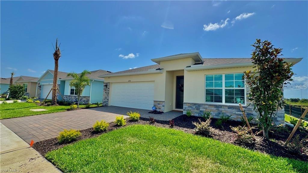 A single-story house features a stone facade, a two-car garage, and a paved driveway — 17710 SHADE TREE LOOP, PUNTA GORDA, FL