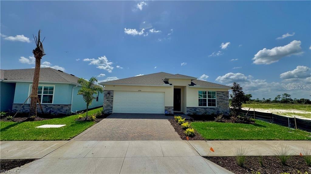 A single-story house with a two-car garage, stone accents, and a paved driveway — 17710 SHADE TREE LOOP, PUNTA GORDA, FL