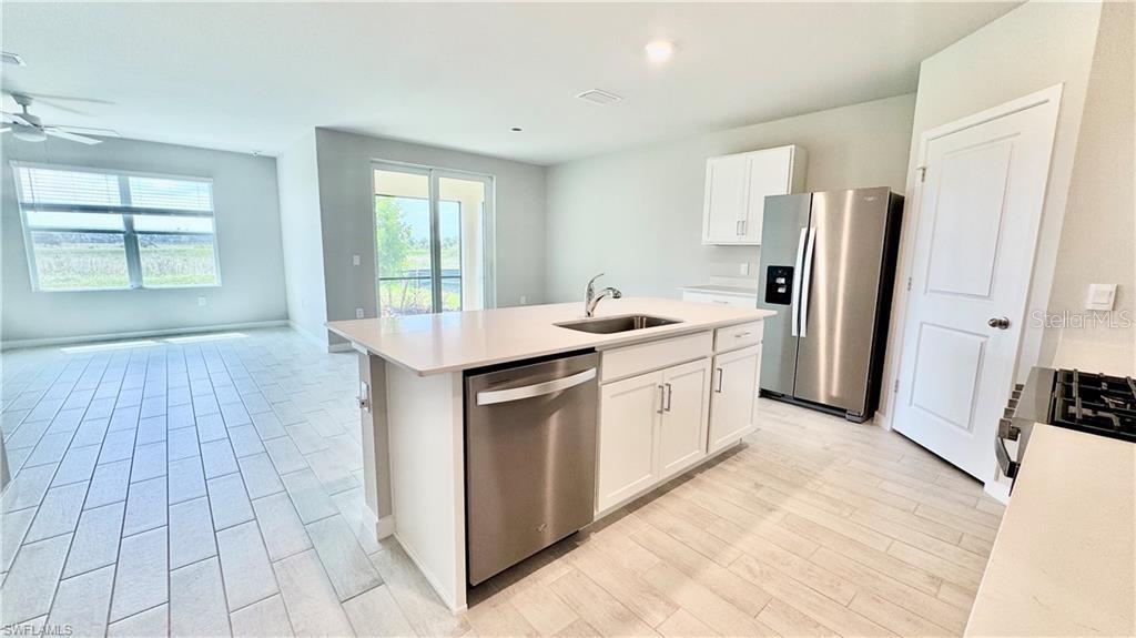 A modern kitchen features a central island with a stainless steel dishwasher and sink — 17710 SHADE TREE LOOP, PUNTA GORDA, FL
