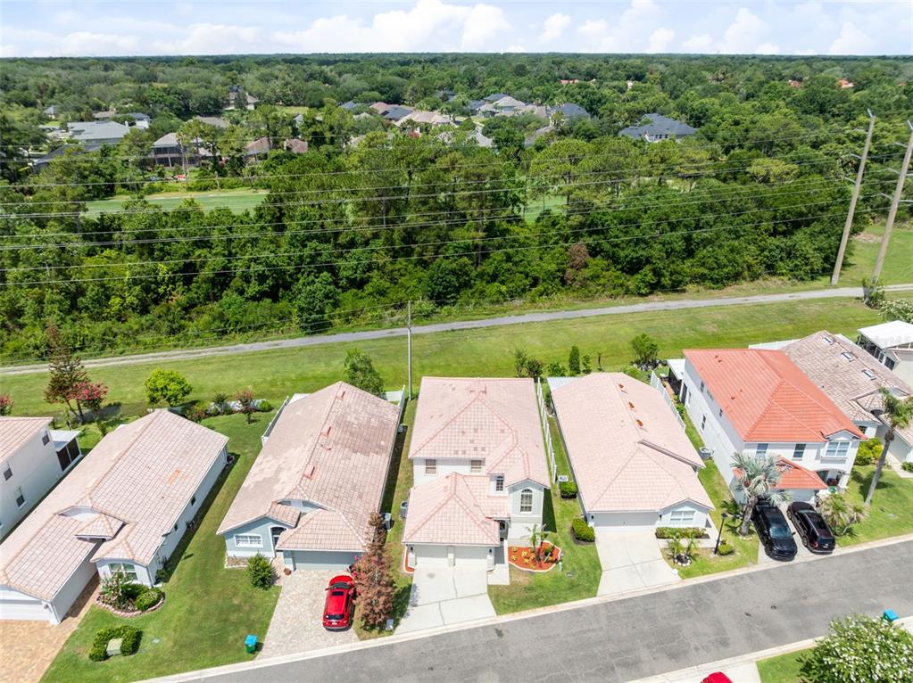 An aerial view shows a row of suburban houses with tile roofs near a golf course — 947 GLEN ABBEY CIRCLE, WINTER SPRINGS, FL
