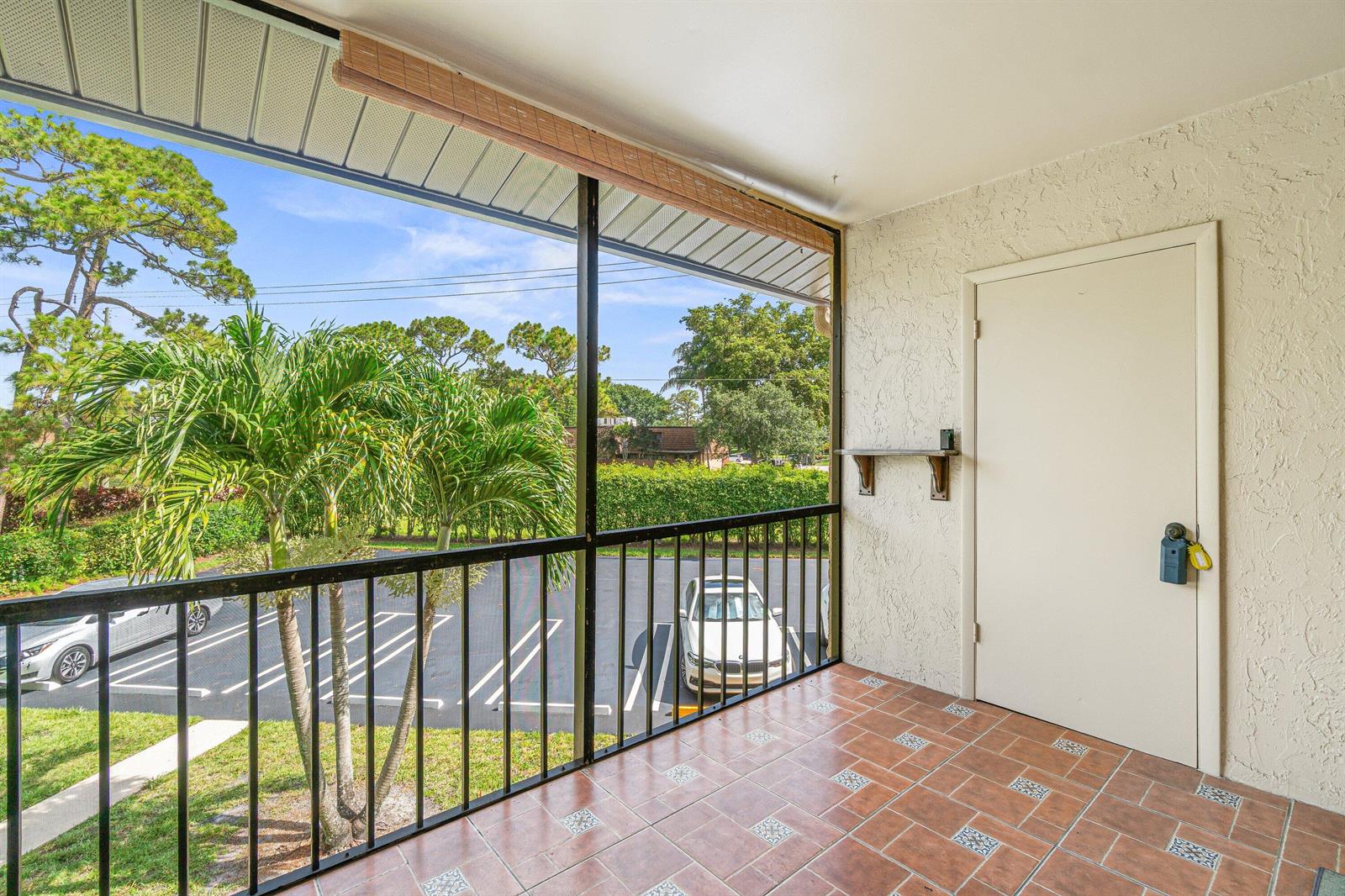 A screened-in balcony features tiled flooring, a white door, and a view of a parking lot — 223 Pine Hov Circle # 2, FL 33463, FL