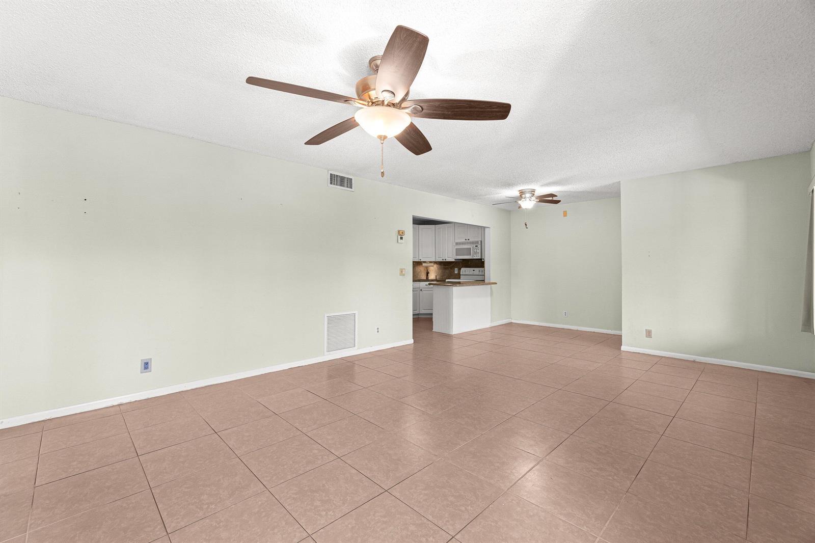 An open living area features light-colored walls, tile flooring, and two ceiling fans — 223 Pine Hov Circle # 2, FL 33463, FL