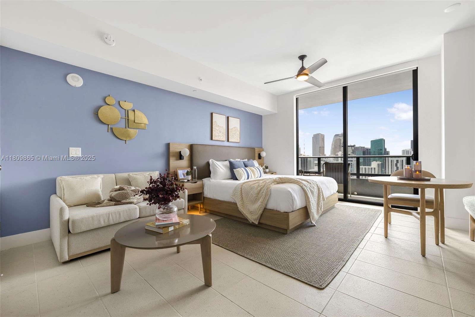 A bedroom features a blue accent wall, a bed, a sofa, and a city view — 159 NE 6th St # 3610, Miami FL 33132, MIAMI, FL