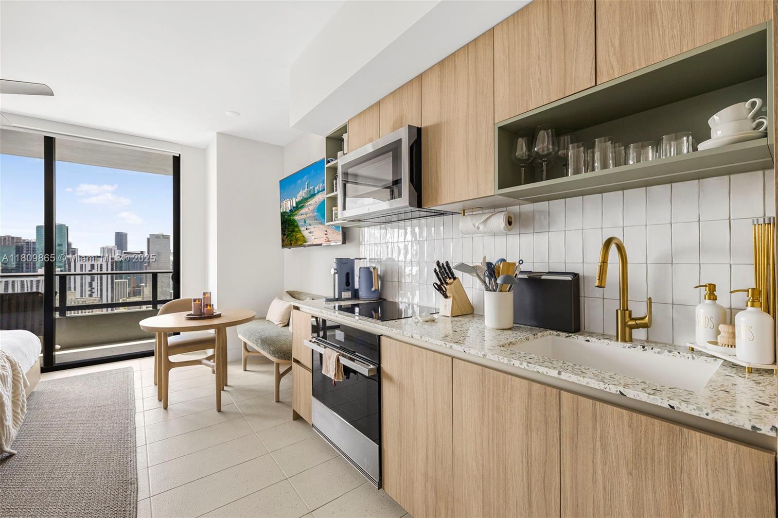 A modern kitchen with light wood cabinets, terrazzo countertops, and a view of city buildings — 159 NE 6th St # 3610, Miami FL 33132, MIAMI, FL