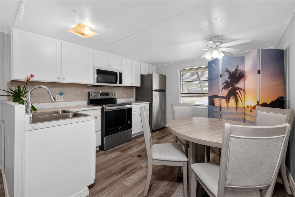 A kitchen with white cabinets, stainless steel appliances, and a round dining table with chairs — 7526 SILAGE CIRCLE, PORT CHARLOTTE, FL