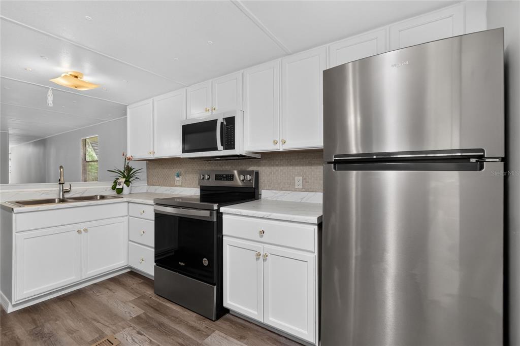 A kitchen with white cabinets, stainless steel appliances, and light-colored countertops — 7526 SILAGE CIRCLE, PORT CHARLOTTE, FL