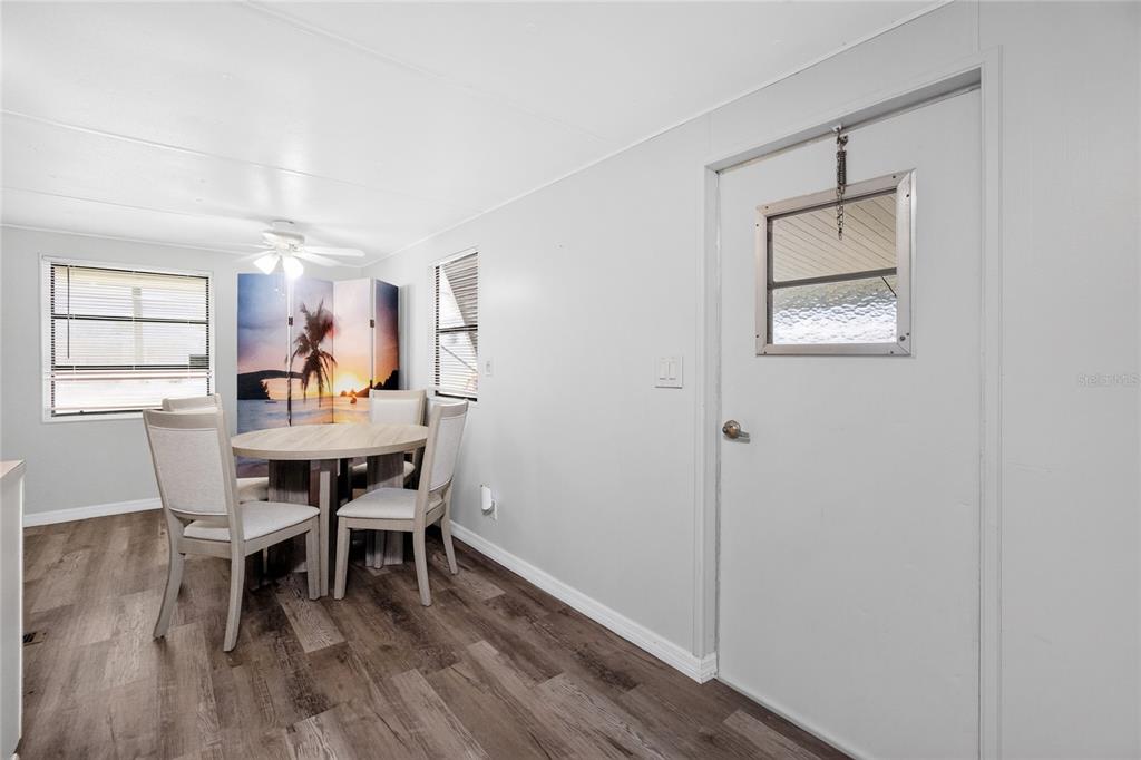 A dining area features a round table, four chairs, wood-look flooring, and a white door — 7526 SILAGE CIRCLE, PORT CHARLOTTE, FL