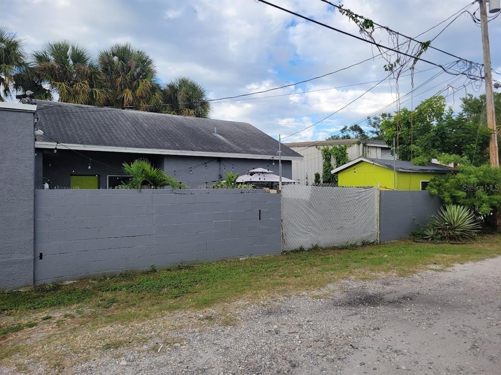 A grey concrete block wall encloses a yard with a grey house and yellow shed — 5205 HAINES ROAD N, ST PETERSBURG, FL