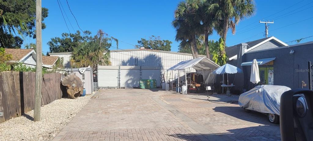 A paved parking area sits between a gray building and a wooden fence — 5205 HAINES ROAD N, ST PETERSBURG, FL