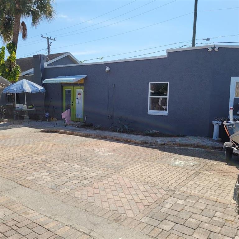 A gray exterior building with a green door, a window, and a brick-paved patio area — 5205 HAINES ROAD N, ST PETERSBURG, FL