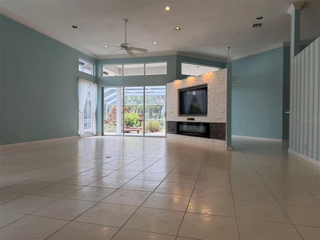 A living room features light blue walls, tile flooring, a stone fireplace wall, and sliding doors — 173 ORANGE TREE DRIVE, ATLANTIS, FL