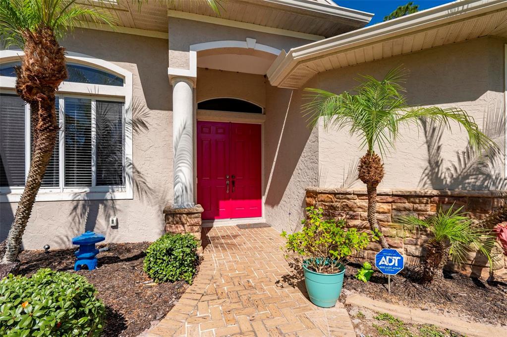 The exterior of a house features a brick walkway leading to bright pink double doors — 4462 LA FRANCE AVENUE, NORTH PORT, FL