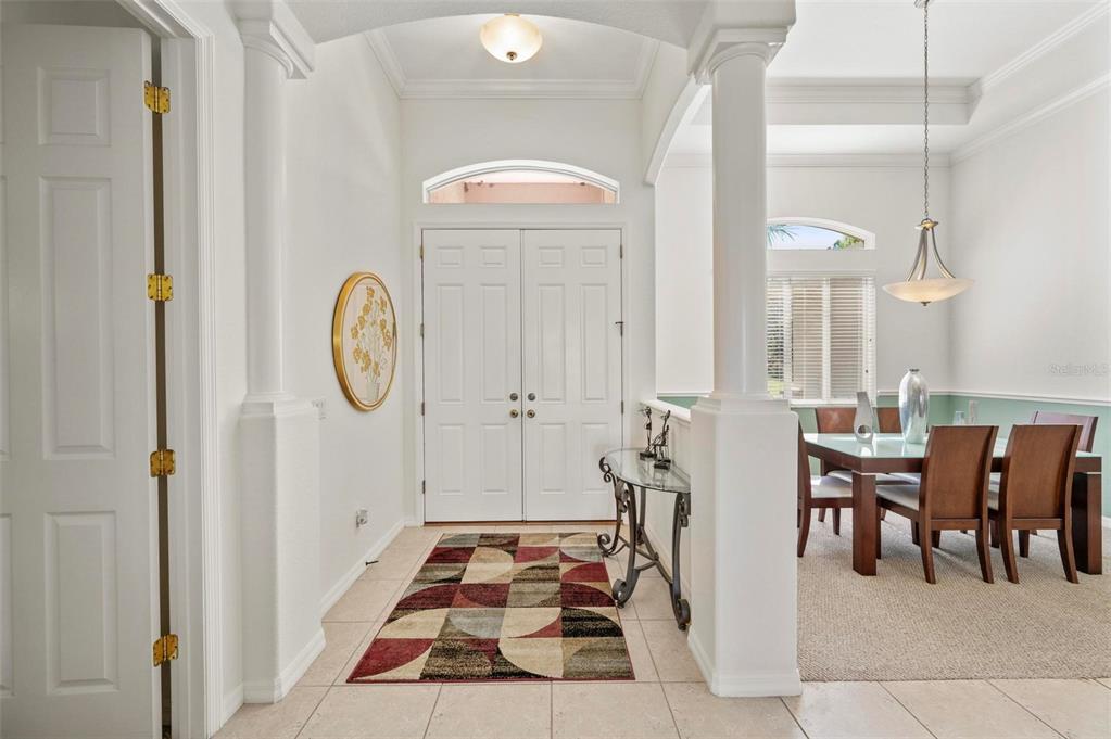 A bright foyer with tile flooring leads to a dining room with columns and windows — 4462 LA FRANCE AVENUE, NORTH PORT, FL