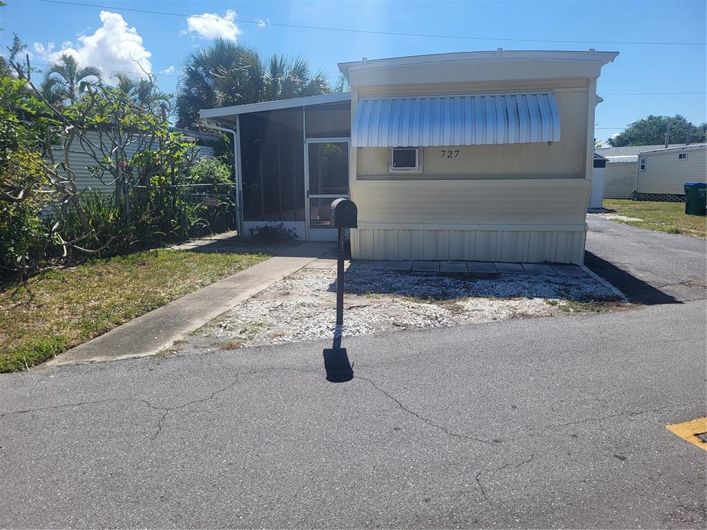 A single-story mobile home with a screened-in porch and a metal awning over the front window — 6580 SEMINOLE BOULEVARD UNIT 727, SEMINOLE, FL