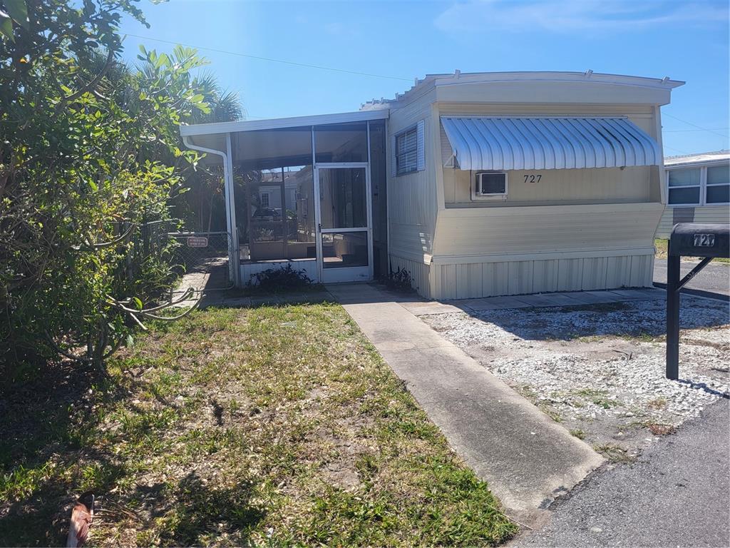A single-story mobile home with a screened-in porch, metal awning, and a concrete walkway — 6580 SEMINOLE BOULEVARD UNIT 727, SEMINOLE, FL
