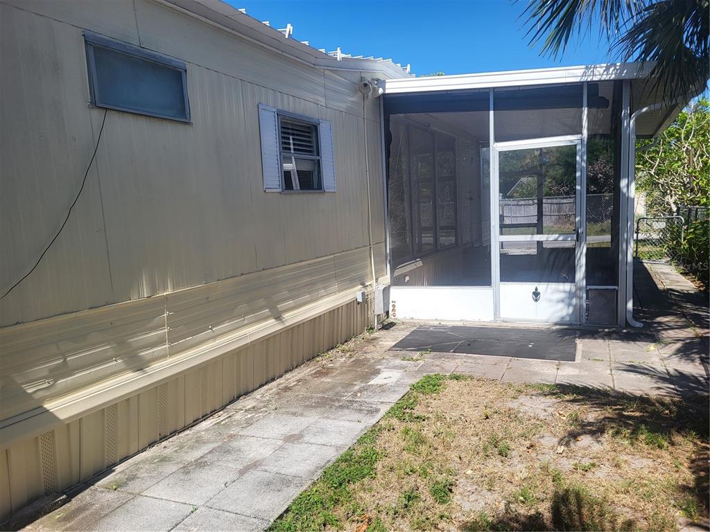 The exterior of a mobile home features a screened-in porch and a paved walkway — 6580 SEMINOLE BOULEVARD UNIT 727, SEMINOLE, FL