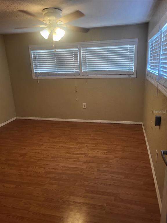 An empty bedroom features light-colored walls, wood-look flooring, a ceiling fan, and two windows — 6580 SEMINOLE BOULEVARD UNIT 727, SEMINOLE, FL