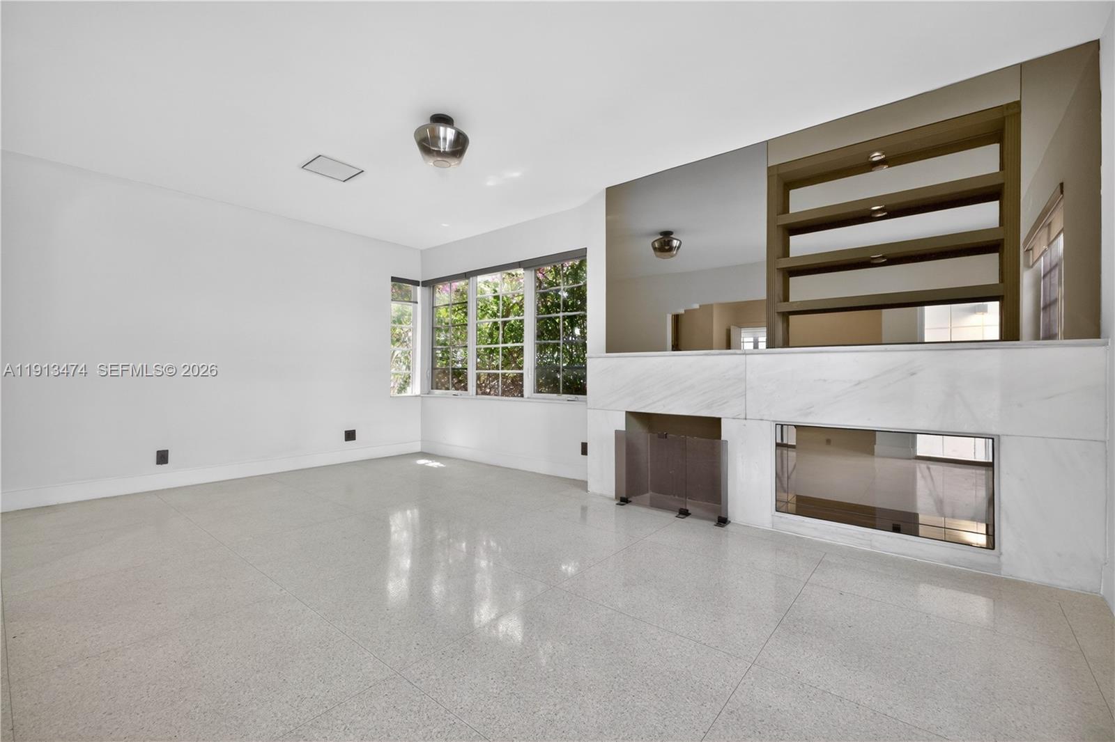 A living room features white tile floors, a marble fireplace, and built-in shelving with mirrors — 1601 Jefferson Ave, Miami Beach FL 33139, MIAMI BEACH, FL