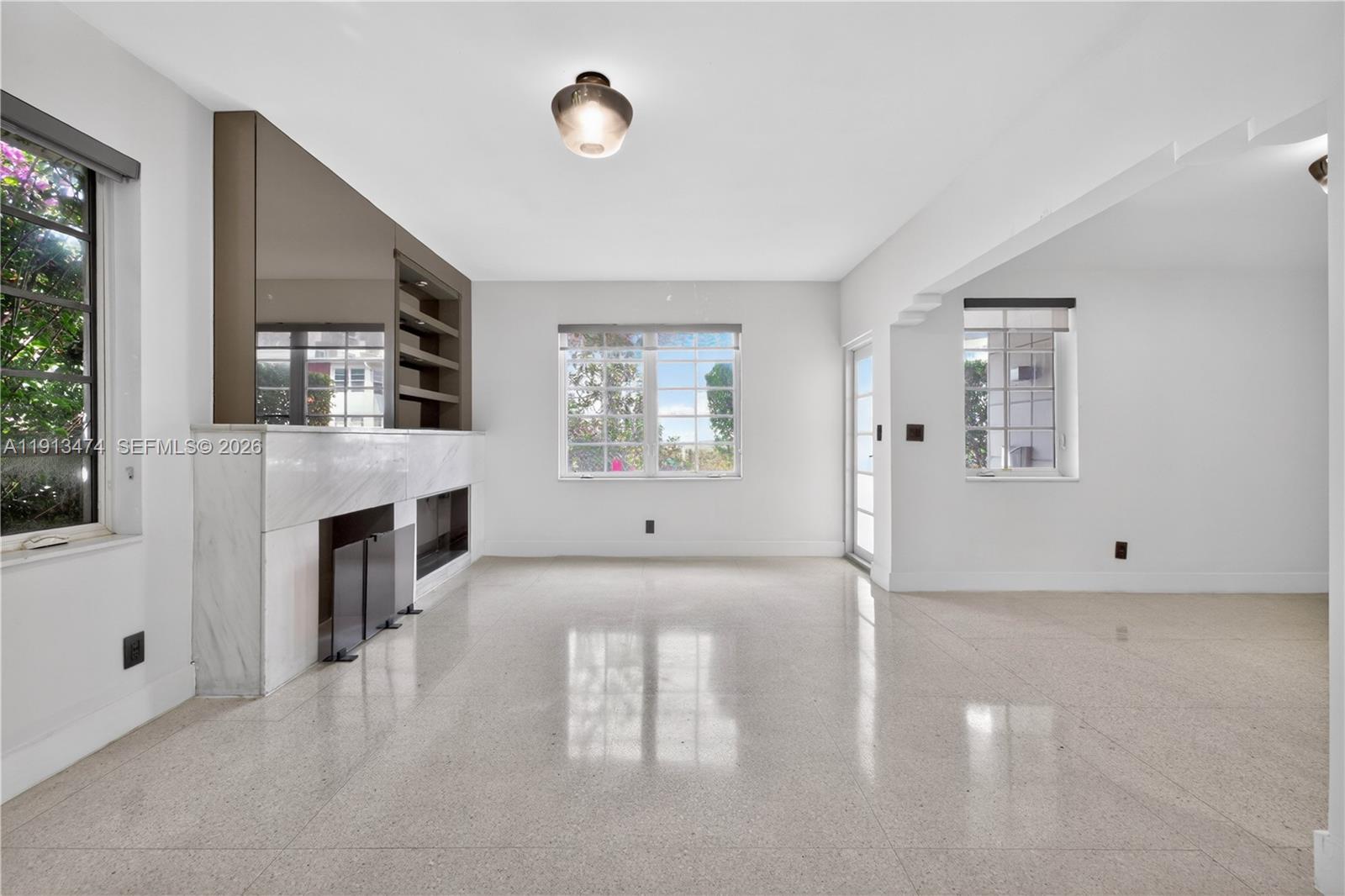 A bright living room features a marble fireplace, built-in shelving, and polished tile flooring — 1601 Jefferson Ave, Miami Beach FL 33139, MIAMI BEACH, FL