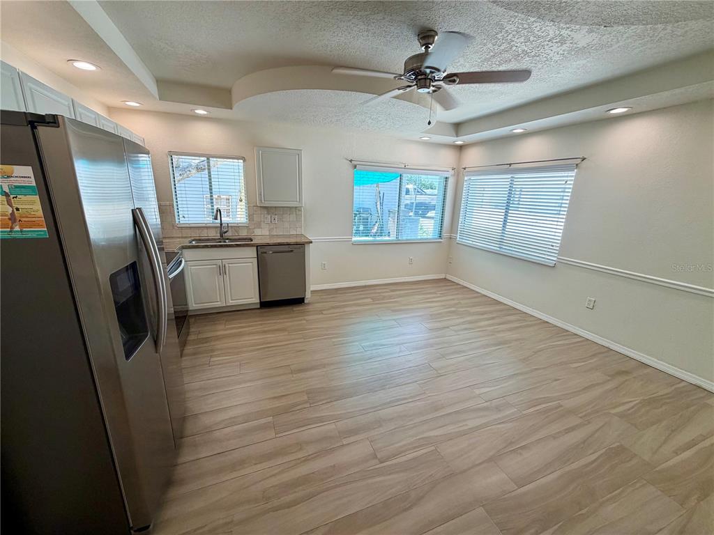 A kitchen with light wood-look flooring, white cabinets, stainless steel appliances, and a ceiling fan — 350 GULF BOULEVARD UNIT 1, INDIAN ROCKS BEACH, FL