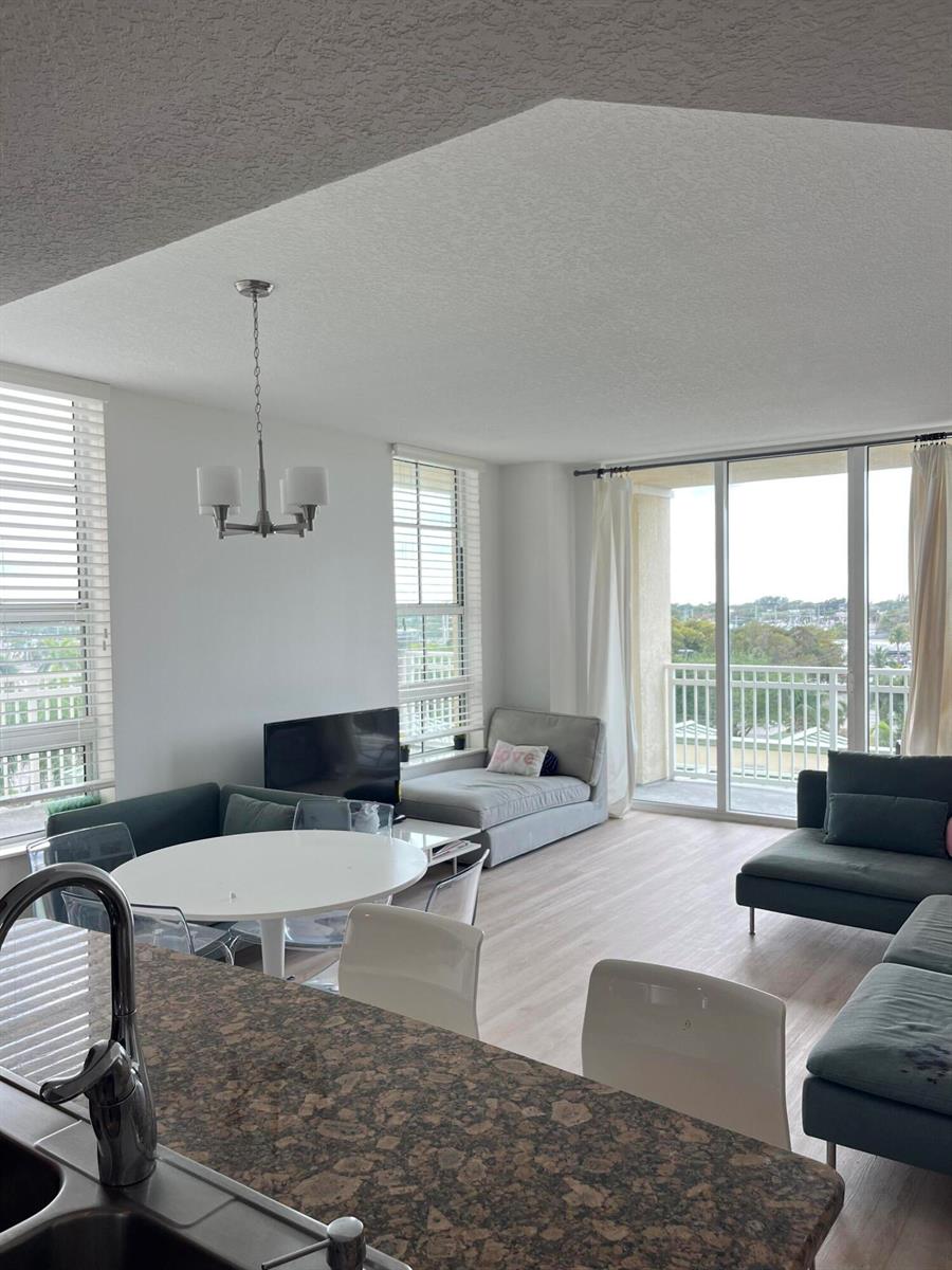 An open-concept living and dining area features a kitchen island, modern furniture, and balcony access — 450 N Federal Highway # 504, Boynton Beach FL 33435, BOYNTON BEACH, FL