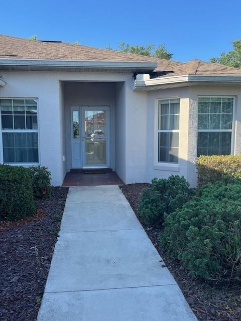 A concrete walkway leads to the front entrance of a light-colored house with windows — 7928 SW 80TH PLACE ROAD, OCALA, FL
