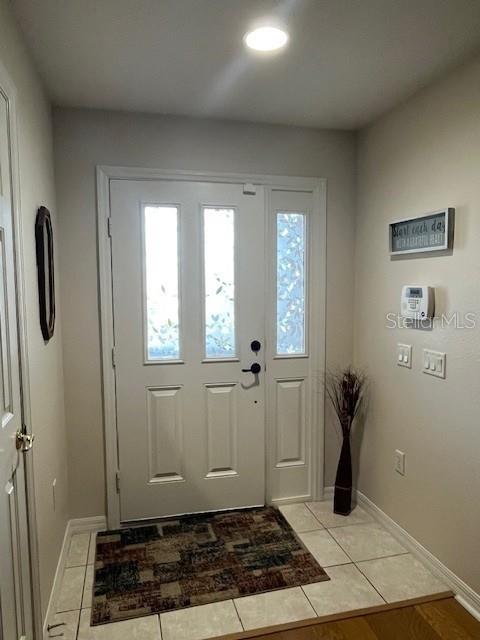 An entryway features a white front door with glass panels, tiled flooring, and neutral walls — 7928 SW 80TH PLACE ROAD, OCALA, FL