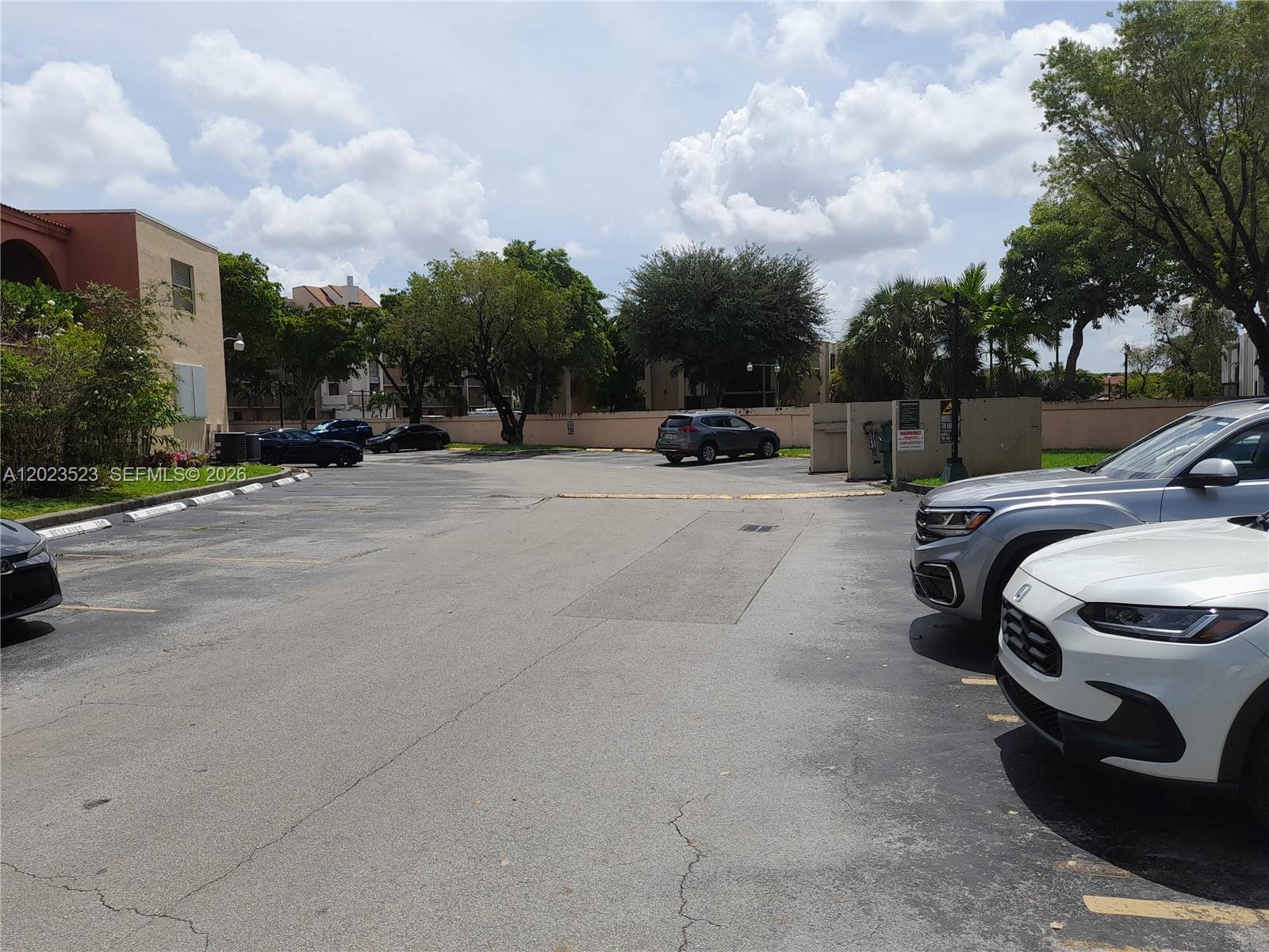 A paved parking lot with several parked cars sits in front of a residential building — 10245 NW 9th St Cir # 9, Miami FL 33172, MIAMI, FL