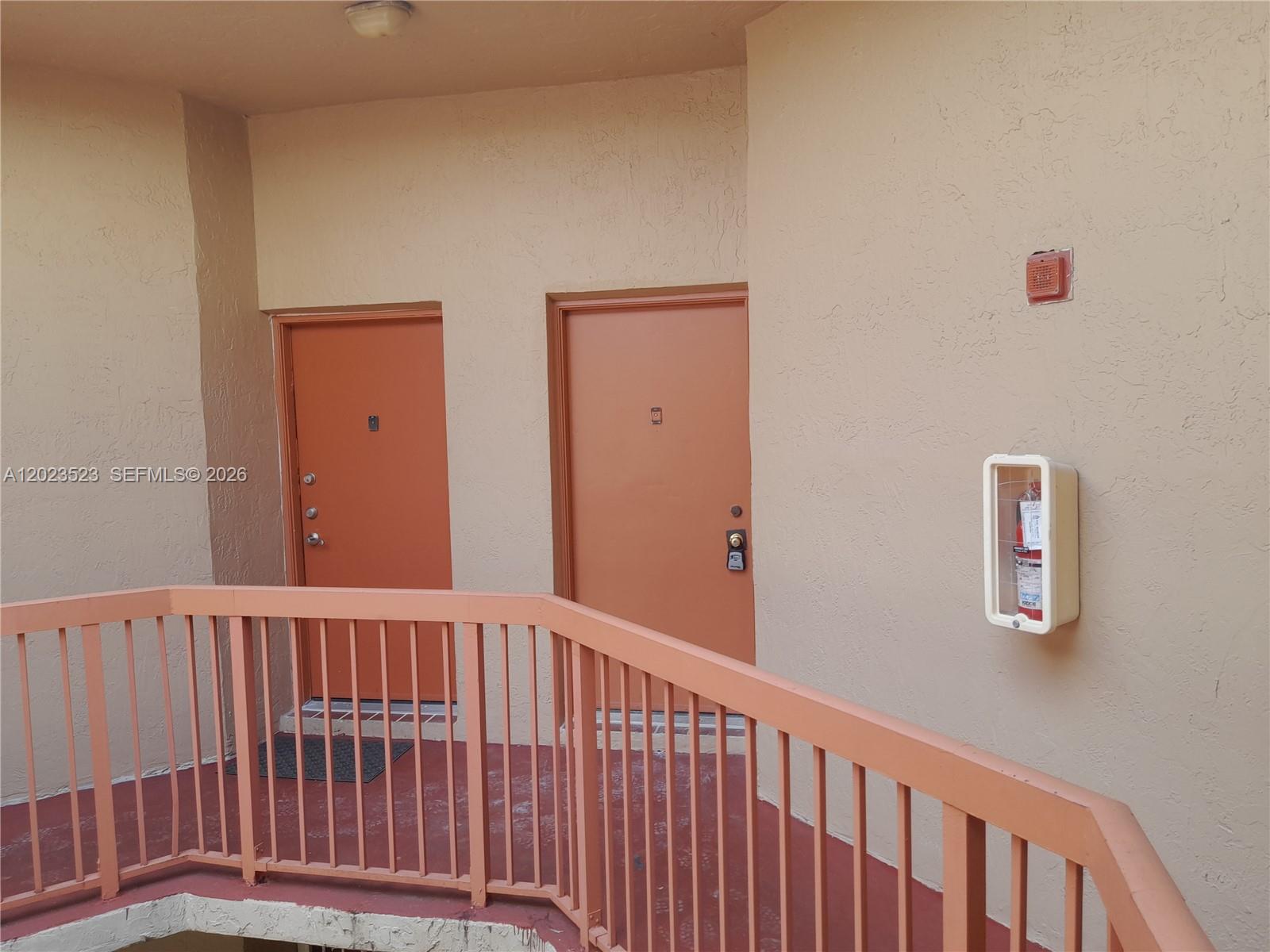 An exterior walkway features two orange doors, a fire extinguisher cabinet, and a metal railing — 10245 NW 9th St Cir # 9, Miami FL 33172, MIAMI, FL