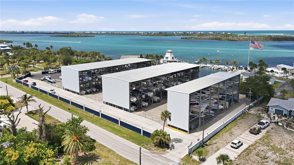 An aerial view shows three large, open-sided boat storage structures near a coastal waterway — 3161 BOURBON STREET, ENGLEWOOD, FL