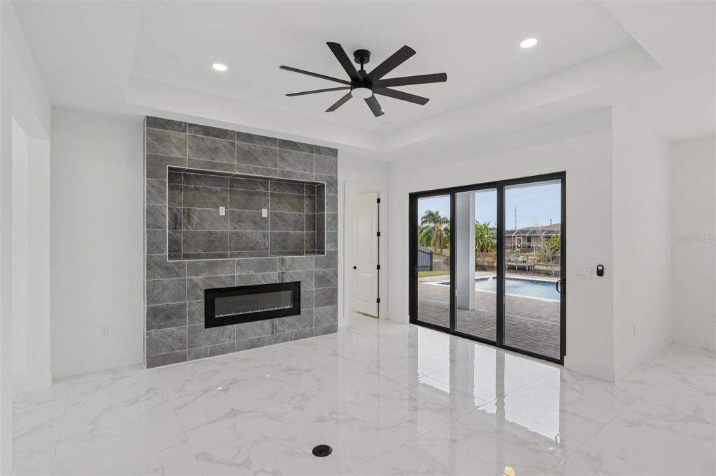 A living room with white marble floors, a gray tiled fireplace wall, and sliding glass doors — 12 SE 17TH AVENUE, CAPE CORAL, FL