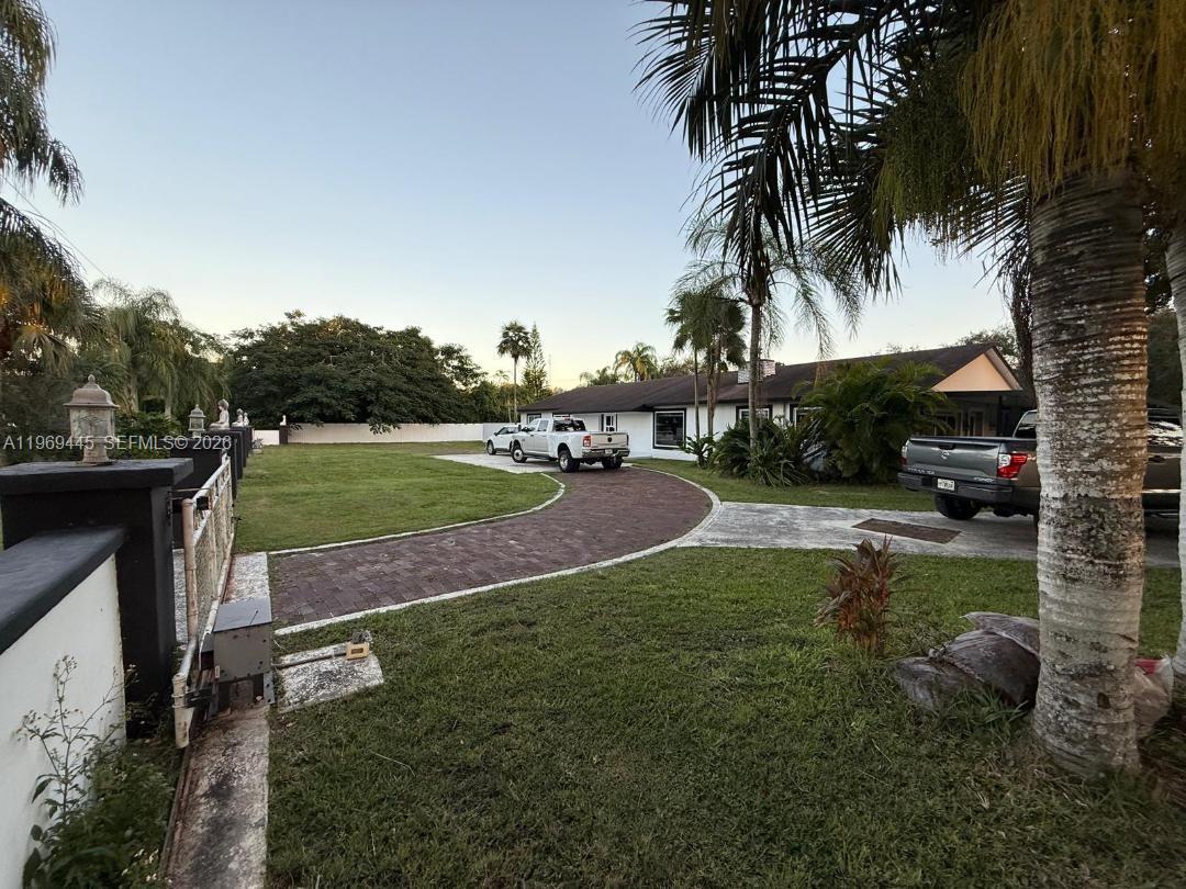 A white house with a brick driveway and palm trees in a grassy yard — 15750 SW 216th St, Miami FL 33170, MIAMI, FL