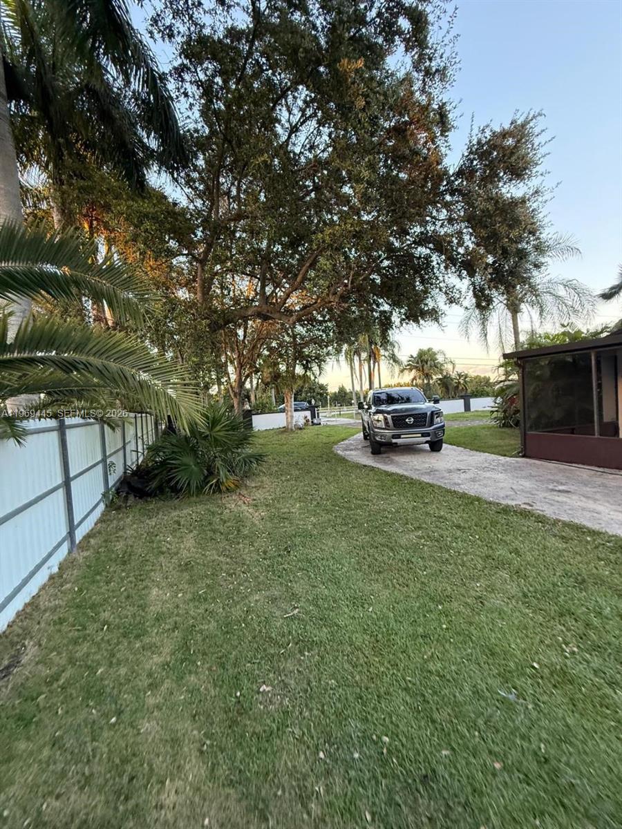 A gray pickup truck is parked on a concrete driveway next to a grassy yard — 15750 SW 216th St, Miami FL 33170, MIAMI, FL