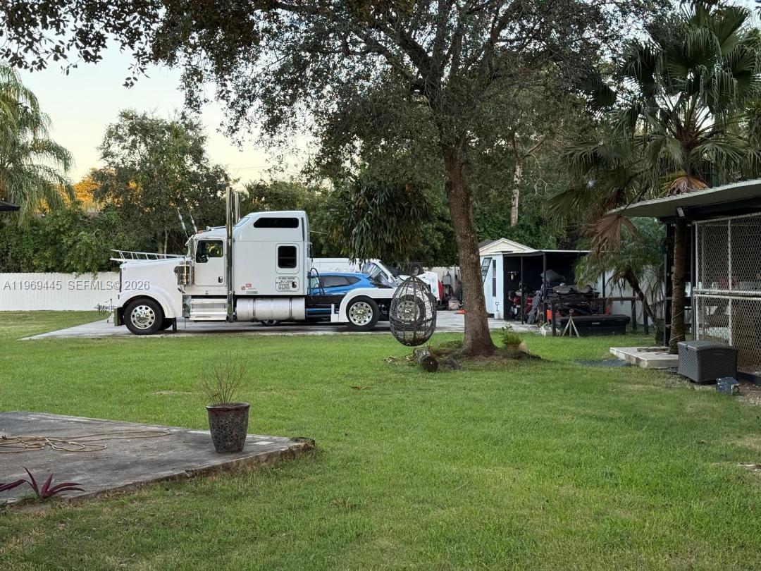 A white semi-truck is parked on a concrete pad in a grassy residential backyard — 15750 SW 216th St, Miami FL 33170, MIAMI, FL