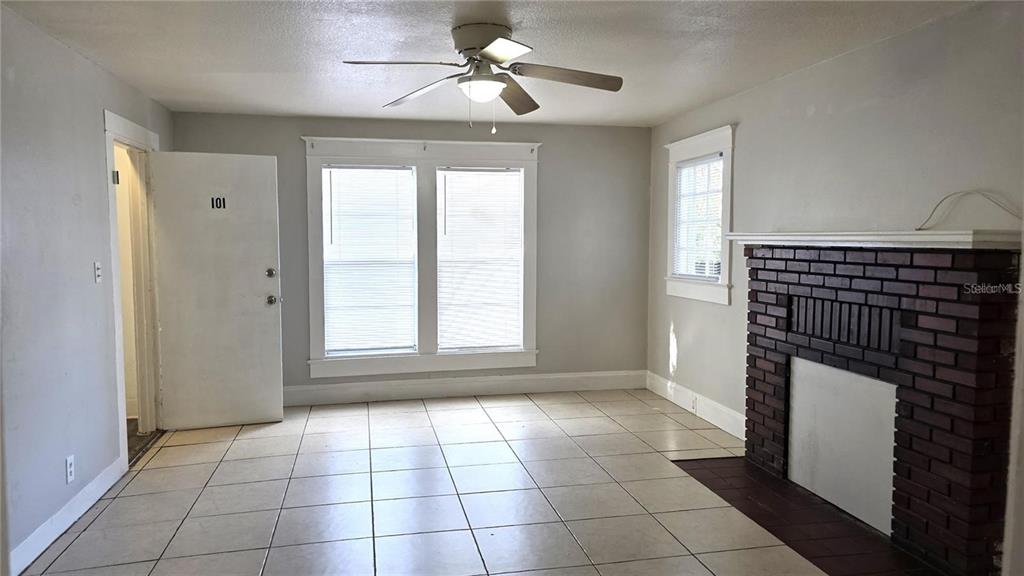 A living room features light tile flooring, a brick fireplace, and a ceiling fan — 1113 S PARK AVENUE, SANFORD, FL