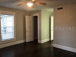 A bedroom features dark hardwood floors, light gray walls, white trim, and two interior doors — 1113 S PARK AVENUE, SANFORD, FL