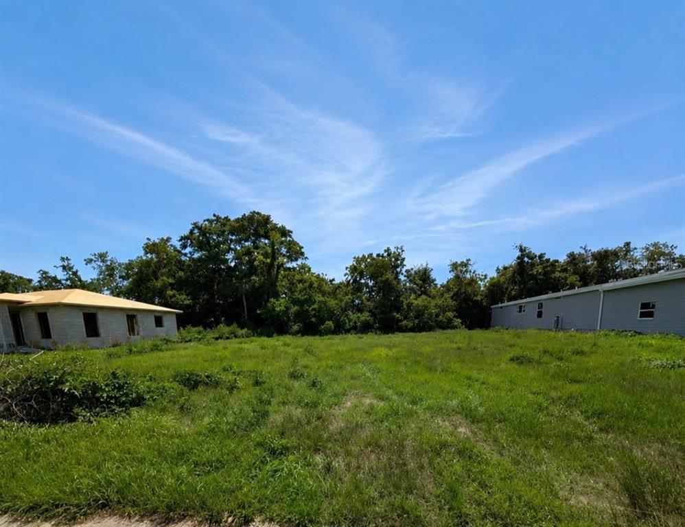 A grassy vacant lot sits between a house under construction and a neighboring building — 15579 CHARMWOOD DRIVE, HUDSON, FL