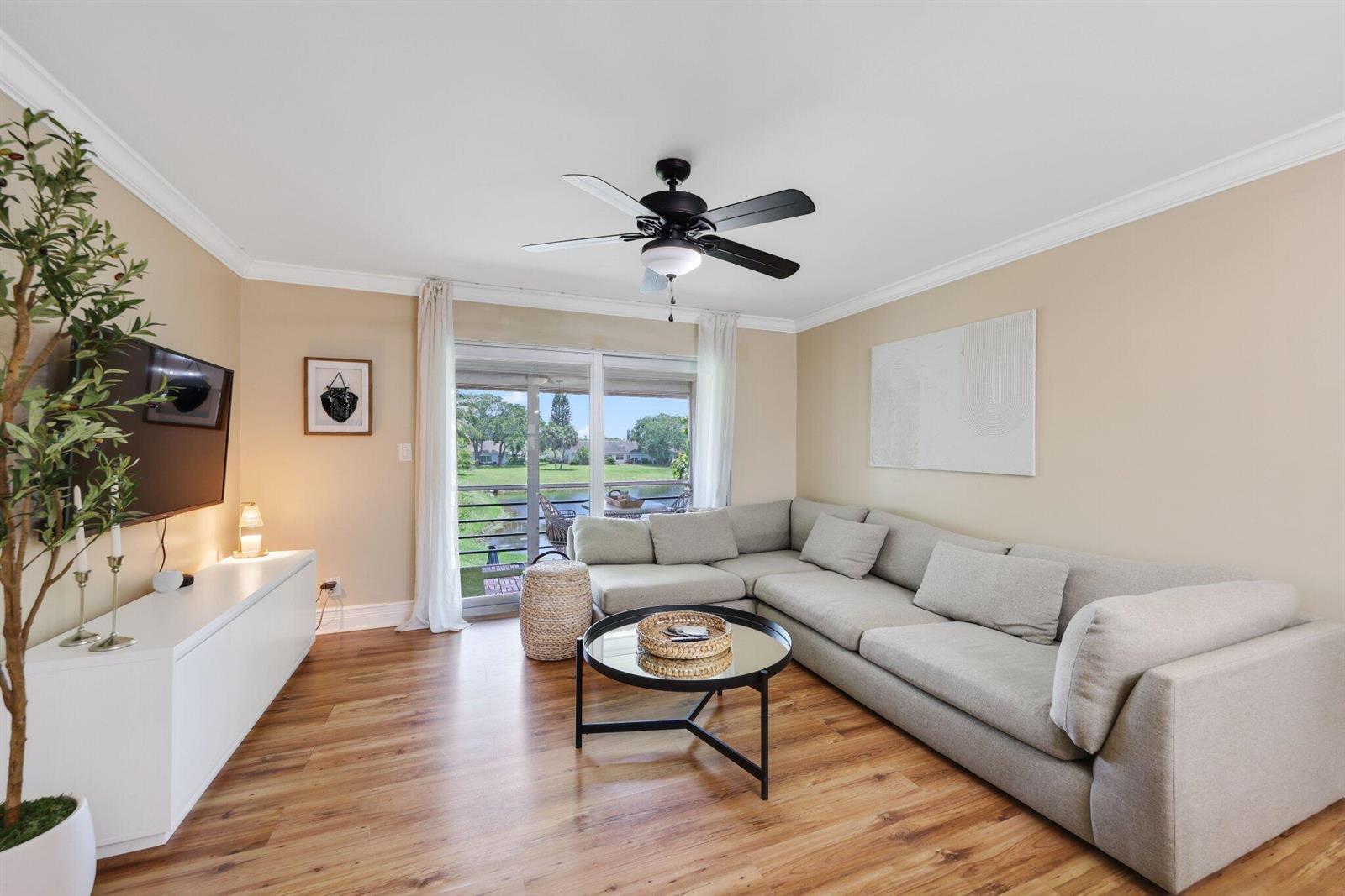 A living room features a sectional sofa, a coffee table, and a view of a pond — 2700 Fiore Way # 2020, Delray Beach FL 33445, DELRAY BEACH, FL
