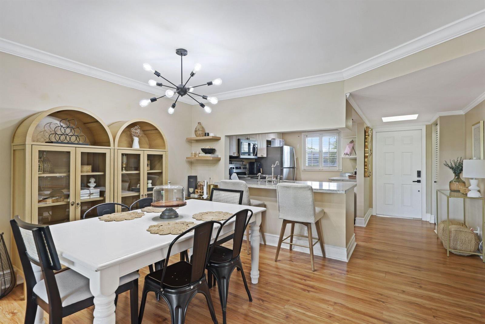 A dining area with a white table, black chairs, and a kitchen pass-through window — 2700 Fiore Way # 2020, Delray Beach FL 33445, DELRAY BEACH, FL