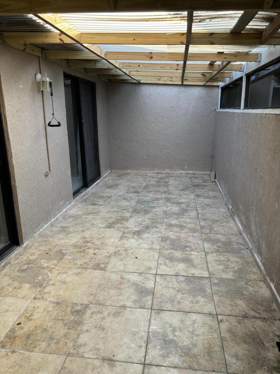 A covered outdoor patio with tiled flooring, stucco walls, and a wooden beam ceiling — 12761 Westhampton Circle, Wellington FL 33414, WELLINGTON, FL