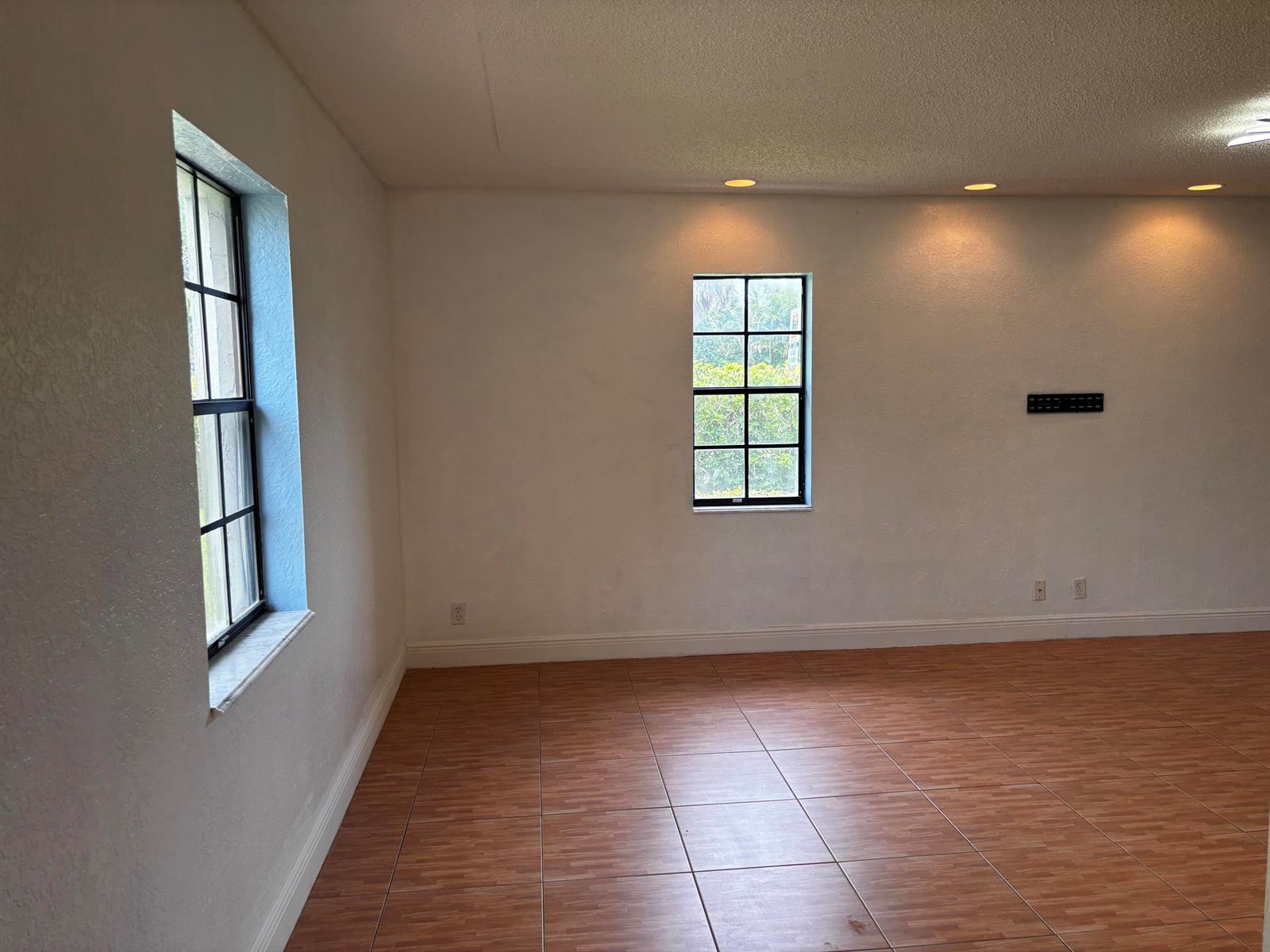 An empty room with wood-look tile flooring, white walls, and two windows — 12761 Westhampton Circle, Wellington FL 33414, WELLINGTON, FL