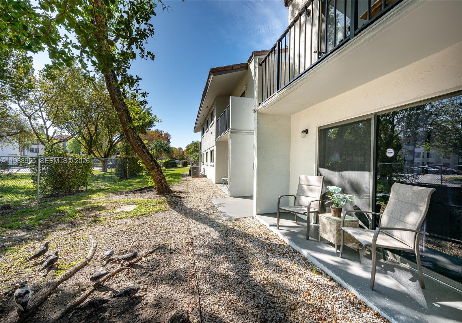 A ground-level patio with two chairs sits outside a multi-story apartment building — 7095 NW 179th St # 110, Hialeah FL 33015, HIALEAH, FL