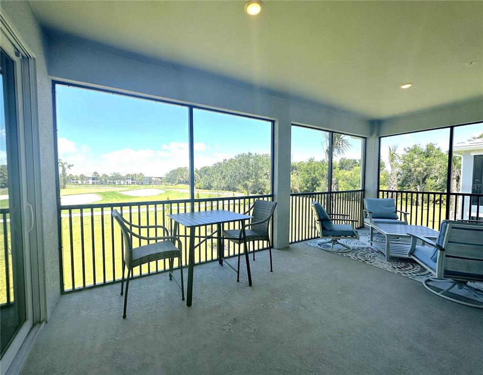 A screened-in patio features a dining set, lounge chairs, and views of a golf course — 4835 BIRCHWOOD COURT UNIT 6222, PUNTA GORDA, FL